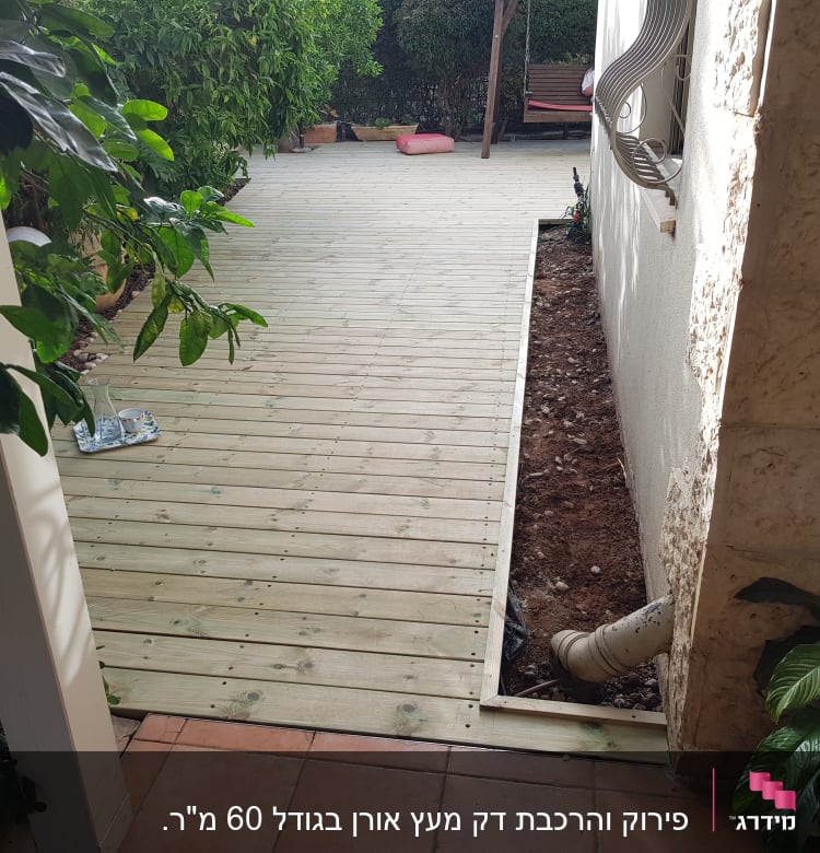 דק עץ בגינה עם צינור ניקוז בצד